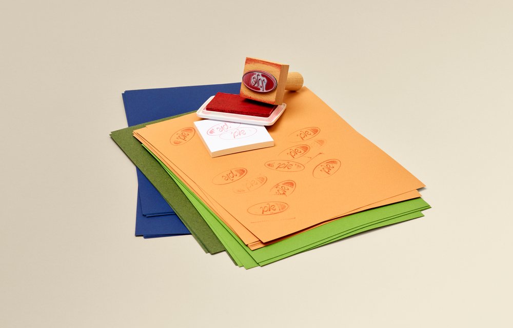 Carimbo com logotipo e almofada de tinta em cima de um papel colorido